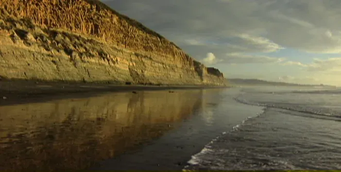 A coastal bluff meeting the shoreline at golden hour